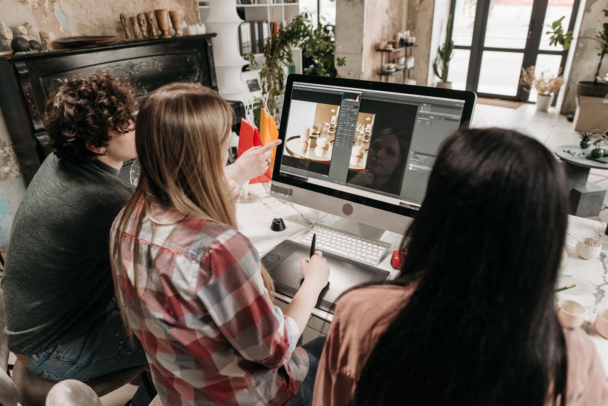 Three designers reviewing a layout together on a desktop screen in a studio