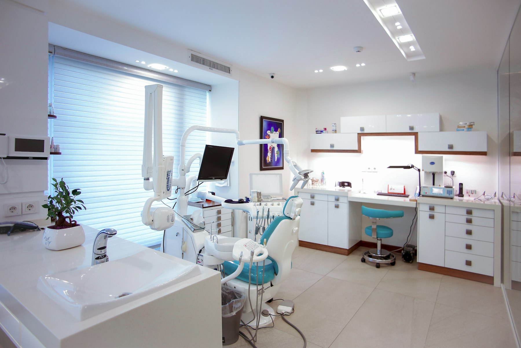 Modern dental surgery with a teal treatment chair and clean white fit-out