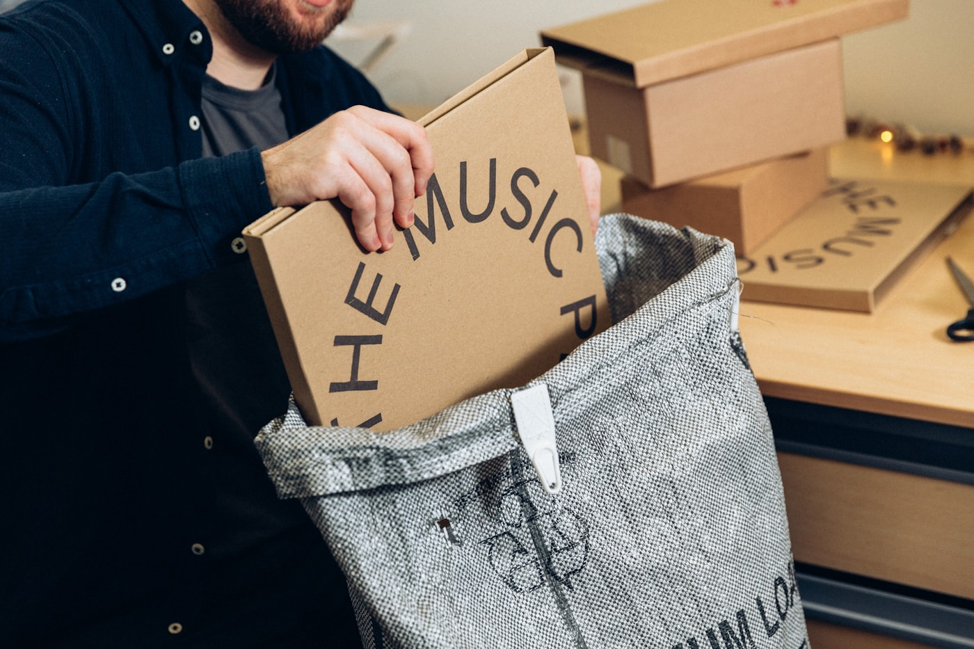 Hands packing a branded box into a courier satchel at an online store
